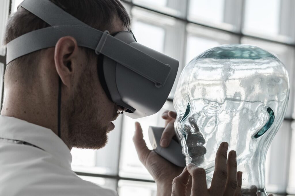 A young doctor wearing VR goggles examining a transparent mannequin in a virtual reality simulation for practice - the future of healthcare concept